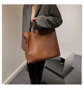 Dettaglio della borsa tote marrone caramello in ecopelle con doppie cinghie e bottone in metallo