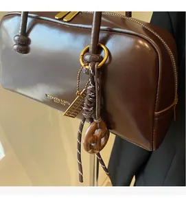 Close-up of vintage dark brown patent leather handbag with unique gold bag charms and logo