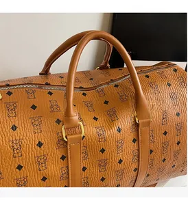 Detail view of large brown travel bag with bear patterns and sturdy double handles