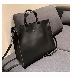 Dettaglio della borsa tote in pelle nera opaca con manici e tracolla regolabile rimovibile