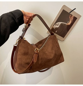 Détail du sac Boston en daim caramel avec boucles dorées mates et textures de bandoulière