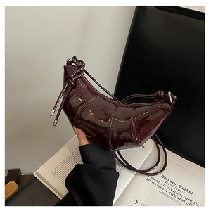 Close-up of glossy deep wine red croissant bag featuring elegant knots and silver metal rings