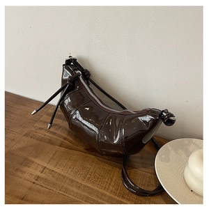 Detail of dark brown patent leather croissant bag with high gloss and metal zipper