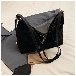 Detailopname van grote zwarte suède hobo tas met goudkleurige gesp en telefoon