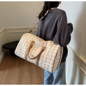 Rear view of a model carrying a large cream travel bag with brown bear patterns