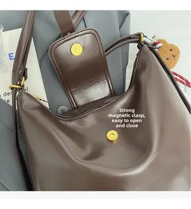 Detail view of strong magnetic clasp and leather texture on a brown shoulder tote bag