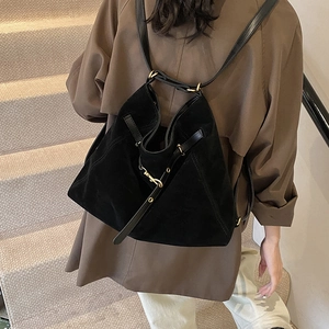 Minimalist black suede backpack with gold hardware and leather straps on model
