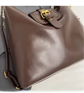Close-up of matte dark brown leather tote bag with elegant gold metal buckle detail