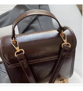 Detail of oil wax leather handbag with golden metal twist lock on grey fabric
