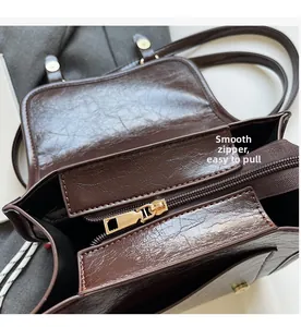 Close-up of golden zipper hardware and smooth wax leather texture on brown tote bag