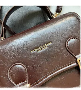 Close-up of deep brown oil wax leather handbag featuring gold embossed fashion lettering
