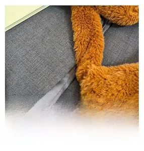 Detail shot of grey woven fabric with high-quality stitching and orange plush fur trim