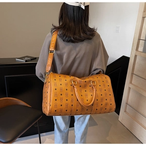 Detail of caramel travel bag featuring vintage bear prints and a wide shoulder strap