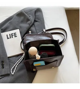Top-down view of spacious interior in a brown PU leather bag with daily essentials