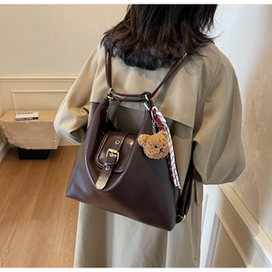 Detail of dark brown vintage faux leather tote bag with brass buckle and teddy bear charm