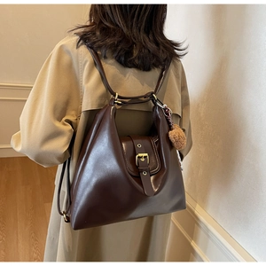 Detail of a vintage large dark brown tote bag with a retro metal buckle and plush ball charm