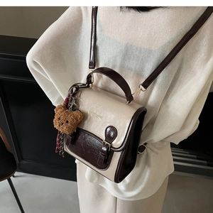Detail of vintage bicolor crossbody bag in cream and coffee leather with a teddy bear charm