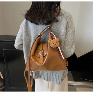 Brown leather tote bag featuring a cute bear pendant and a stylish plaid scarf detail