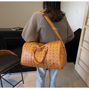 Caramel travel bag with monogram bear print shown on a model in a minimalist setting