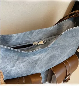 Detail of silver smooth metal zipper on vintage denim and brown leather tote bag