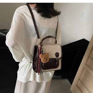 Detailed back view of a minimalist cream and coffee mini backpack with cute bear pendant