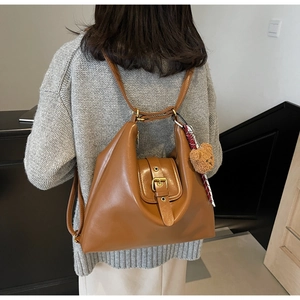 Detail view of brown vintage leather tote with metal buckle and plush bear pendant detail
