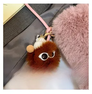 Détail d'un monstre en peluche marron avec bonnet blanc et crochet en métal doré