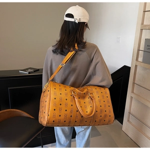 Detailed view of brown travel bag with bear monogram print and wide shoulder strap