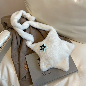 Detail of white star-shaped plush crossbody bag on brown blazer and book background