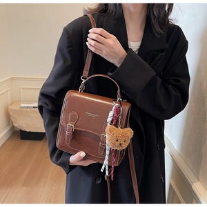 Detail of vintage brown leather satchel with plush bear charm and silk ribbon on strap
