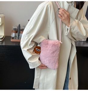 Détail d'un sac bandoulière rose pelucheux avec un pendentif en peluche aux grands yeux