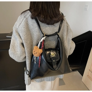 Detail view of a black vintage hobo bag with a plush bear charm on a female model