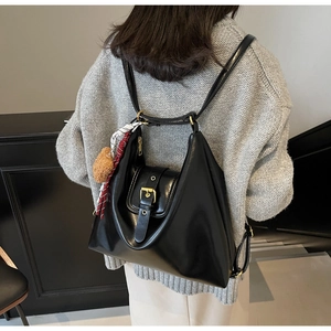 Detail of black leather multi-way tote bag with gold buckle and plush bear charm
