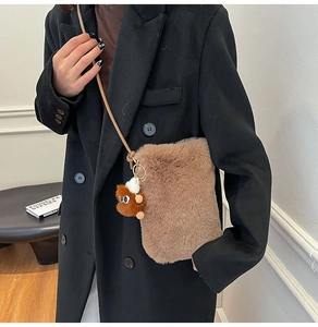 Gros plan du sac bandoulière en peluche marron avec breloque poupée et sangle d'épaule