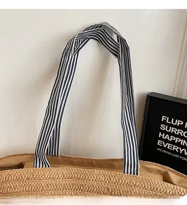 Close-up of woven straw tote bag featuring blue and white striped fabric long straps