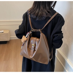 Brown vintage leather backpack for women with a cute plush bear charm on the side
