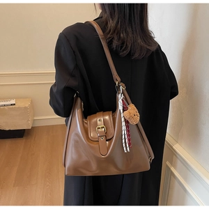 Detail of vintage brown hobo bag featuring plush bear charm and buckle on black coat