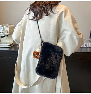 Détail d'un sac bandoulière noir en fausse fourrure avec breloque ours et fine sangle