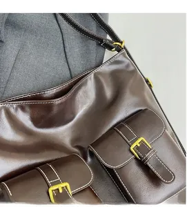 Detail of vintage brown leather tote bag with gold buckle pockets and white stitching