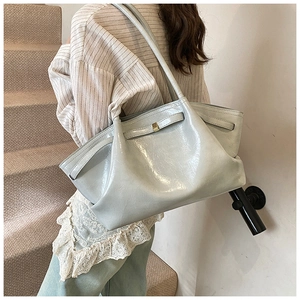 Detail of light grey-green leather tote bag with pleated texture and golden buckle