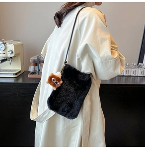 Détail du sac bandoulière en peluche noire avec breloque monstre et bandoulière en cuir