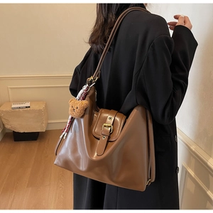 Brown vintage faux leather tote bag with plush bear charm and checkered scarf detail