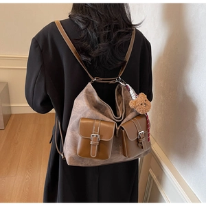 Close-up of retro brown backpack with double front pockets and a cute bear keychain