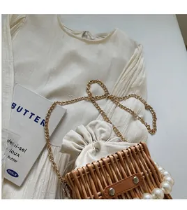Close-up of woven bucket bag with pearl chain details on a white pleated dress