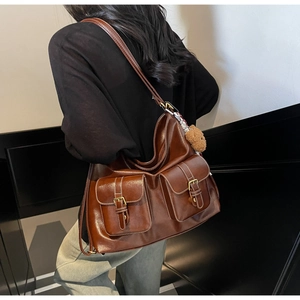 Detail of retro brown tote bag with white stitching, dual front pockets and bear charm