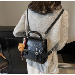 Close-up of black wrinkled faux leather mini backpack with gold hardware and bear charm