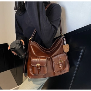 Detail of vintage brown tote bag with dual front pockets and a cute bear charm