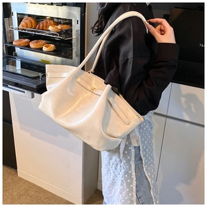 Detail of a large cream pleated shoulder bag with glossy finish in a lifestyle setting