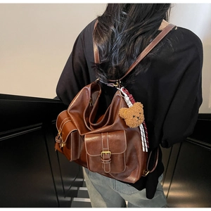 Detail showing the dark brown leather texture and multiple pockets on the vintage backpack