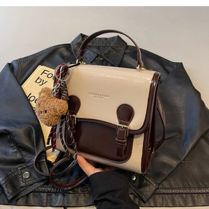 Detailed close-up of retro color-block handbag with gold lettering and plush bear charm